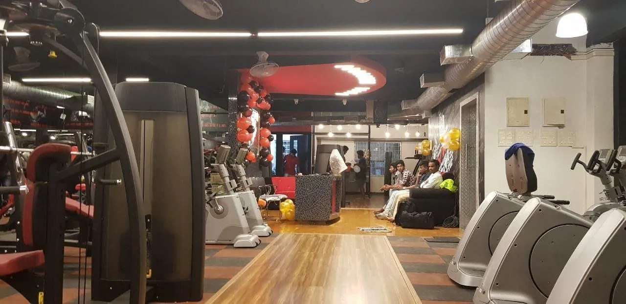Industrial-Style Gym with Exposed Ductwork, Cardiovascular Training Zone, and Modern Ambient Lighting Fitness Showroom Desk and Decor 