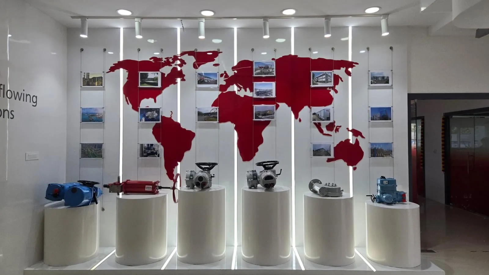 World Map Graphic with Suspended Photo Frames and Circular Pedestal Displays with Glass Partitions at Deskanddecor